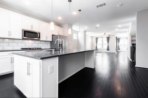 a kitchen with stainless steel appliances kitchen island granite countertop a stove a sink a refrigerator and a microwave