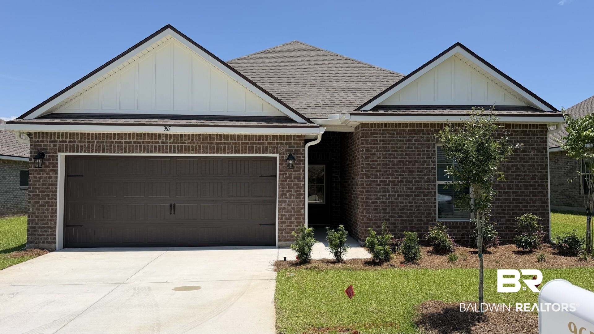 965 Ashville Circle Foley, AL 36535 - Photo 1 of 3 Brick exterior with a dark brown garage door, featuring architectural gables with vertical siding
