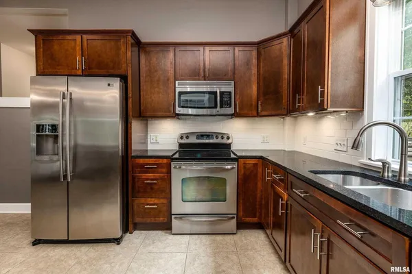 a kitchen with kitchen island granite countertop stainless steel appliances and a refrigerator