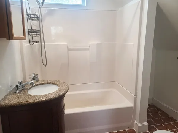 a bathroom with a granite countertop sink a mirror and a bathtub
