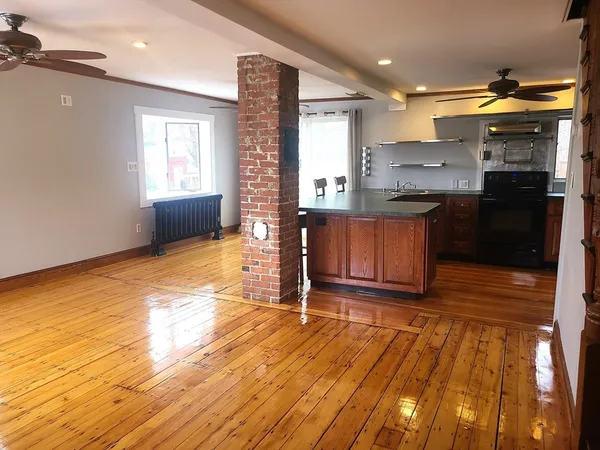 a kitchen with granite countertop wooden floors a sink cabinets and appliances