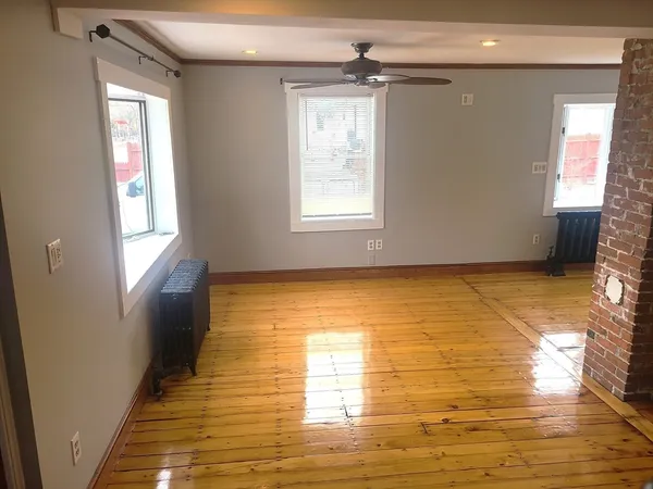 a view of empty room with window and wooden floor