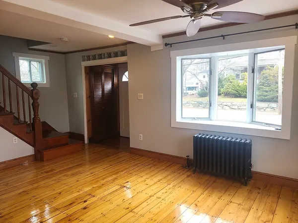 a view of an empty room with wooden floor and a window