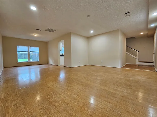 an empty room with wooden floor and windows