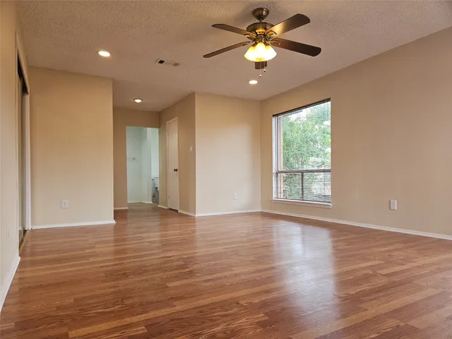 a view of an empty room with a window and wooden floor