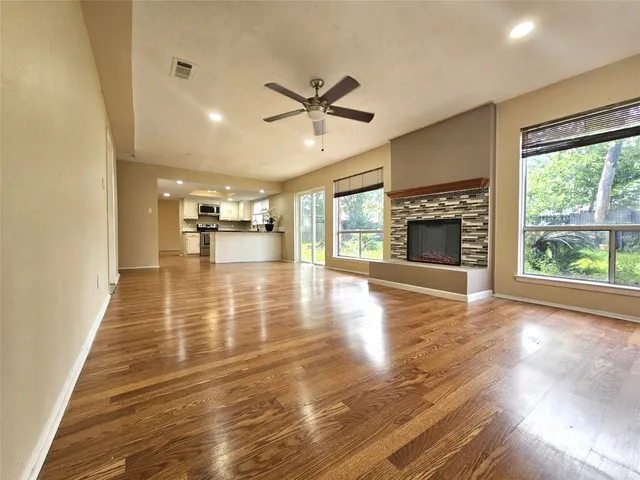 a view of an empty room with window and wooden floor