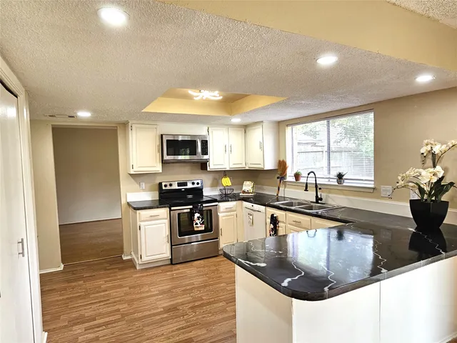 a kitchen with granite countertop a sink a counter top space and stainless steel appliances
