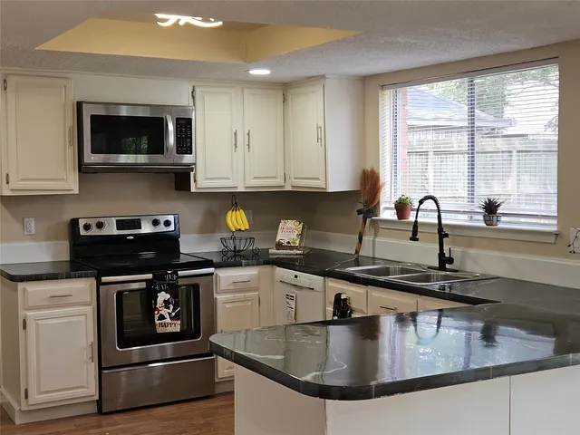 a kitchen with stainless steel appliances granite countertop a sink a stove and a microwave
