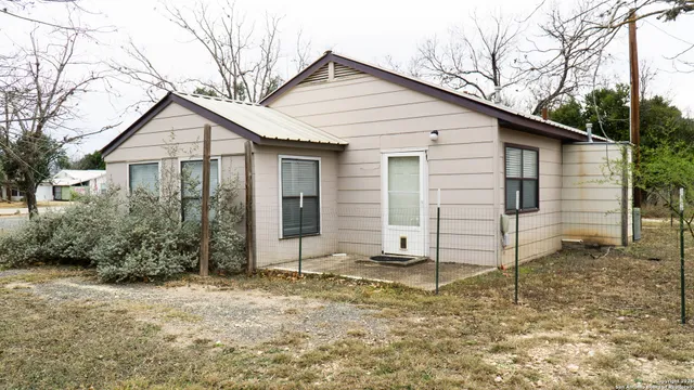 a white house that has a small yard and large trees