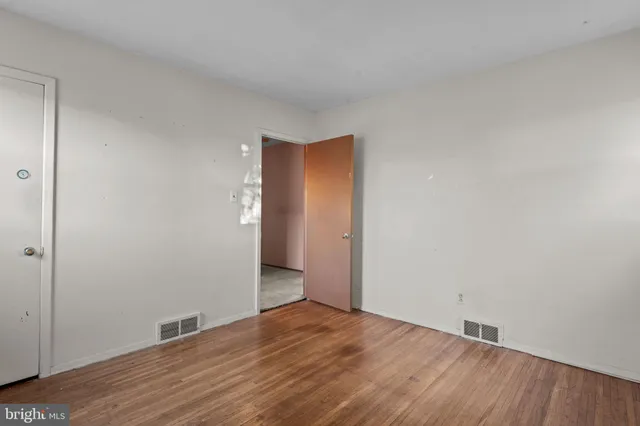 a view of an empty room with wooden floor and closet
