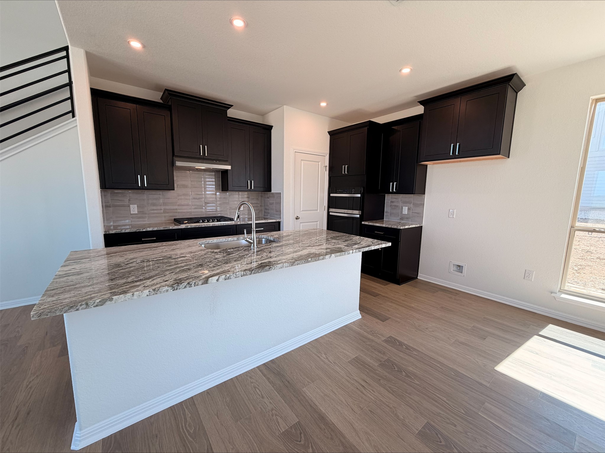 323 Elephant Island Loop Kyle, TX 78640 - Photo 5 of 15 a large kitchen with stainless steel appliances kitchen island granite countertop a stove a sink and a microwave