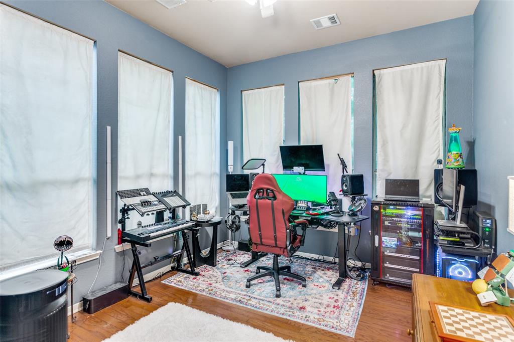 9117 Ripley Street Fort Worth, TX 76244 - Photo 13 of 35 Room featuring light blue walls, wood-finish flooring, and multiple windows with white window coverings