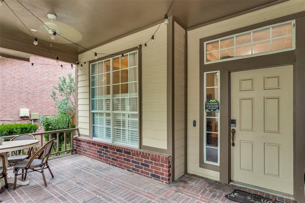 9117 Ripley Street Fort Worth, TX 76244 - Photo 2 of 35 Covered brick-paved patio featuring a paneled entry door with sidelight and transom windows, large multi-pane window with interior plantation shutters, and string lighting