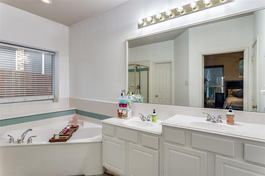 9117 Ripley Street Fort Worth, TX 76244 - Photo 25 of 35 Bathroom featuring a corner soaking tub with deck-mounted fixtures, a dual vanity with white cabinetry, a large wall-mounted mirror, and overhead strip lighting