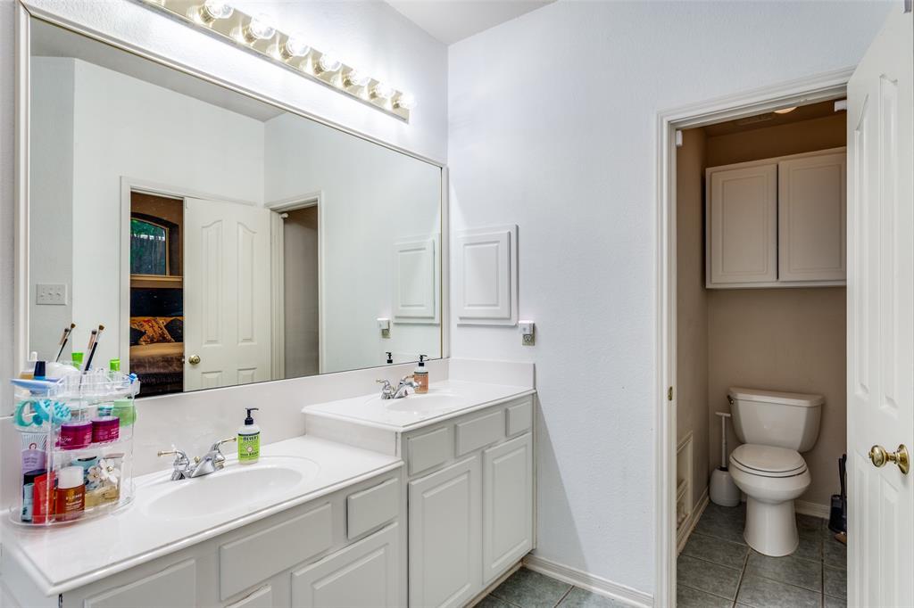 9117 Ripley Street Fort Worth, TX 76244 - Photo 32 of 35 Double vanity with white cabinetry, integrated sinks, chrome faucets, and a full-width mirror