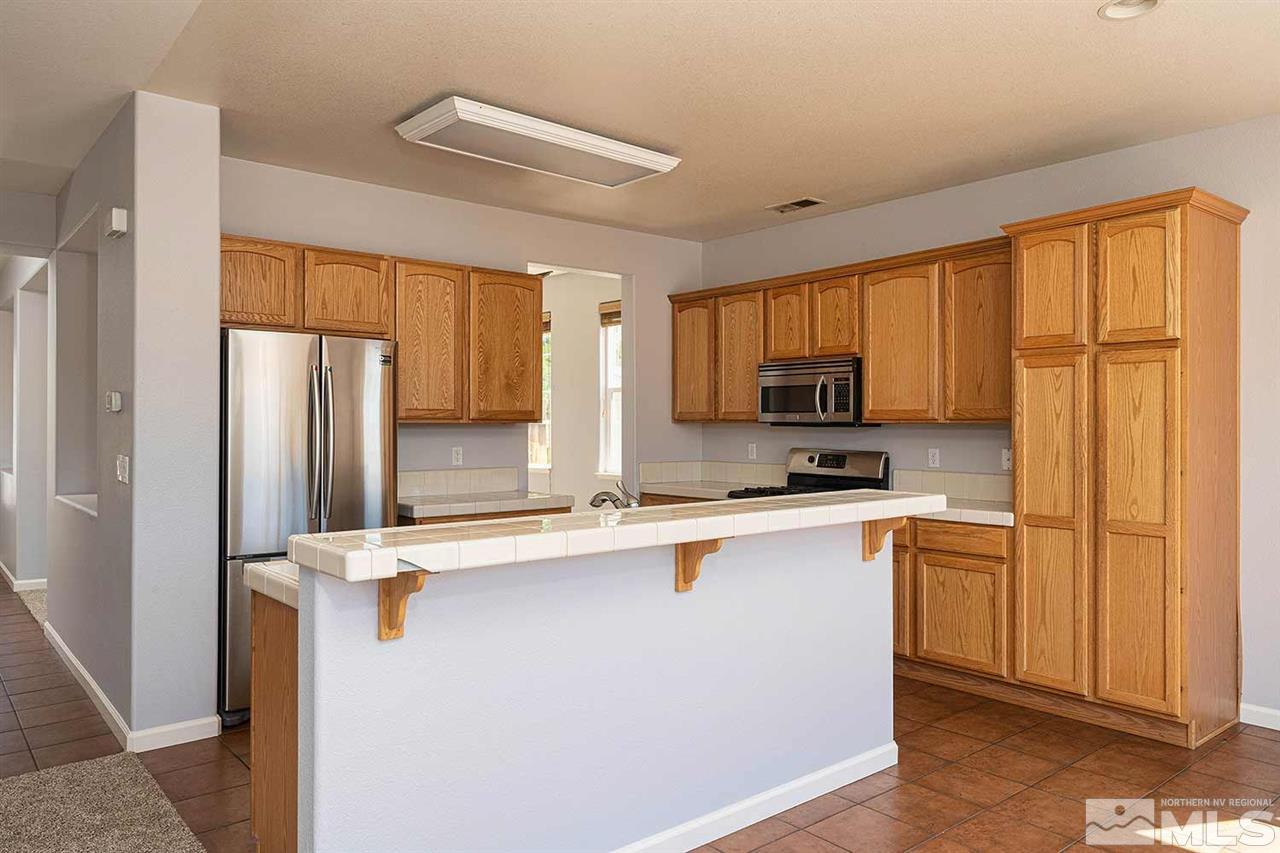 3443 Weaver Place Reno, NV 89512 - Photo 6 of 23 a kitchen with stainless steel appliances granite countertop a refrigerator a sink dishwasher a stove top oven a refrigerator and white cabinets with wooden floor