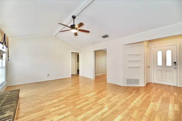 a view of empty room with wooden floor and fan