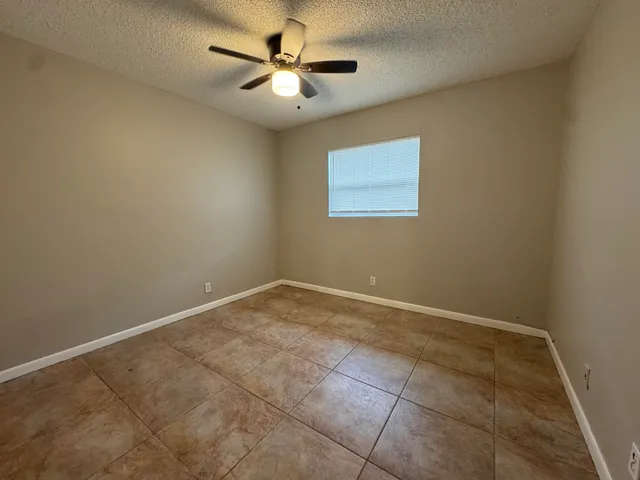 an empty room with a ceiling fan and a window