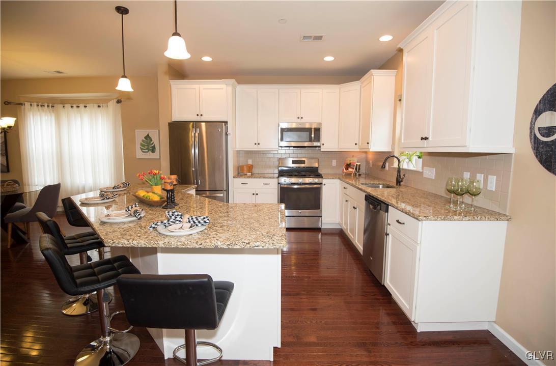 2406 Gentle Hollow Road Whitehall, PA 18052 - Photo 8 of 37 a kitchen with stainless steel appliances granite countertop a stove refrigerator a sink a dining table and chairs with wooden floor