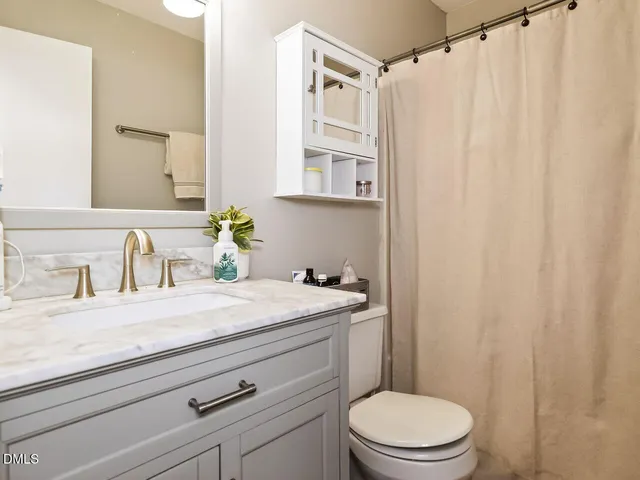 a bathroom with a granite countertop sink vanity mirror and toilet