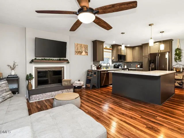 a living room with stainless steel appliances furniture a flat screen tv and a kitchen view