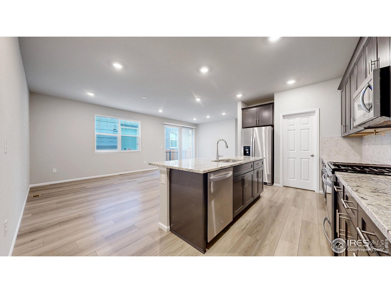 229 East 4th Street Berthoud, CO 80513 - Photo 14 of 49 a open kitchen with kitchen island a sink wooden floor and white stainless steel appliances