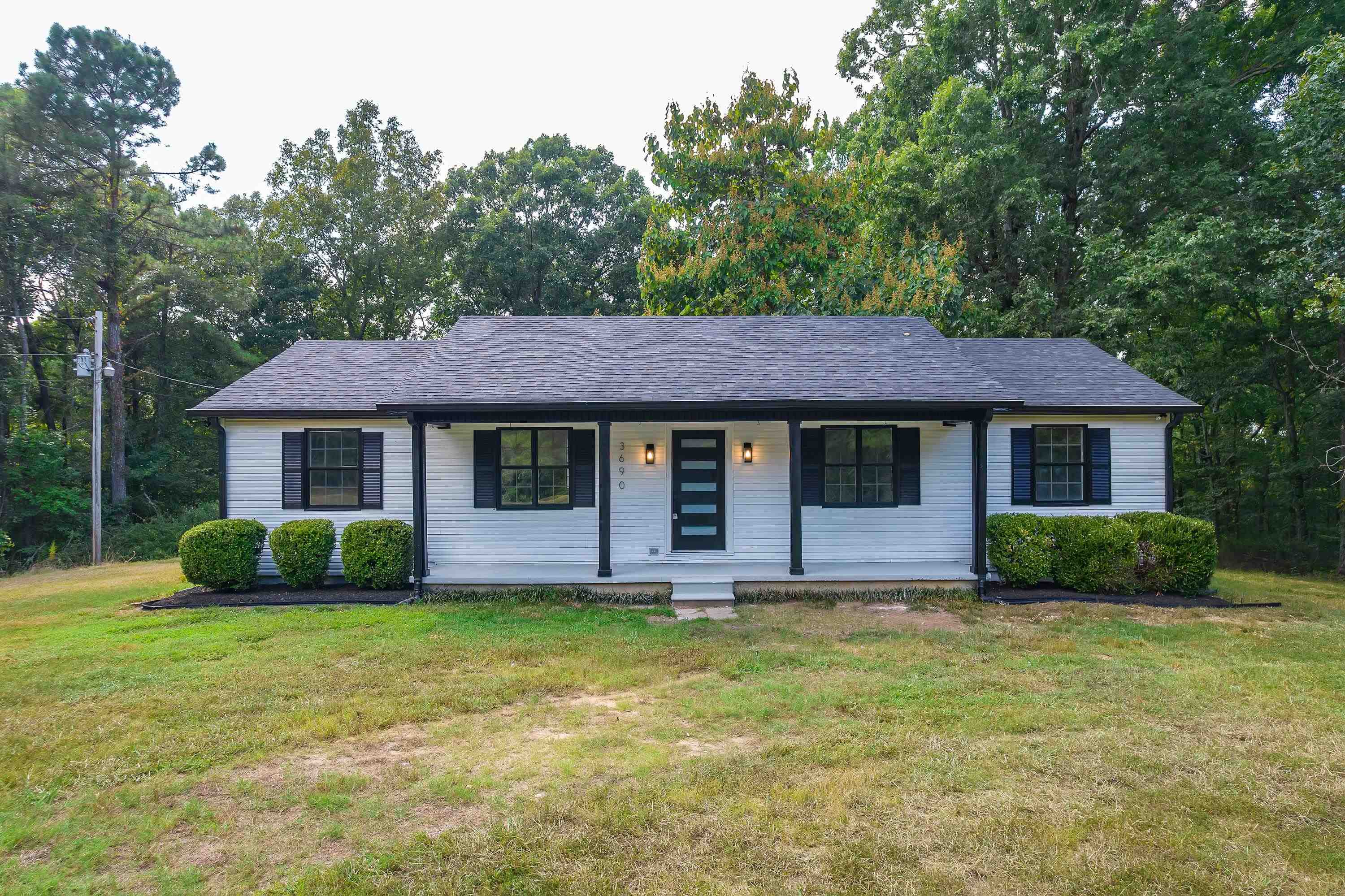3690 Callahan Road Middleton, TN 38052 - Photo 1 of 26 White horizontal siding exterior with dark shutters, a front porch with dark support columns, and a dark asphalt shingle roof