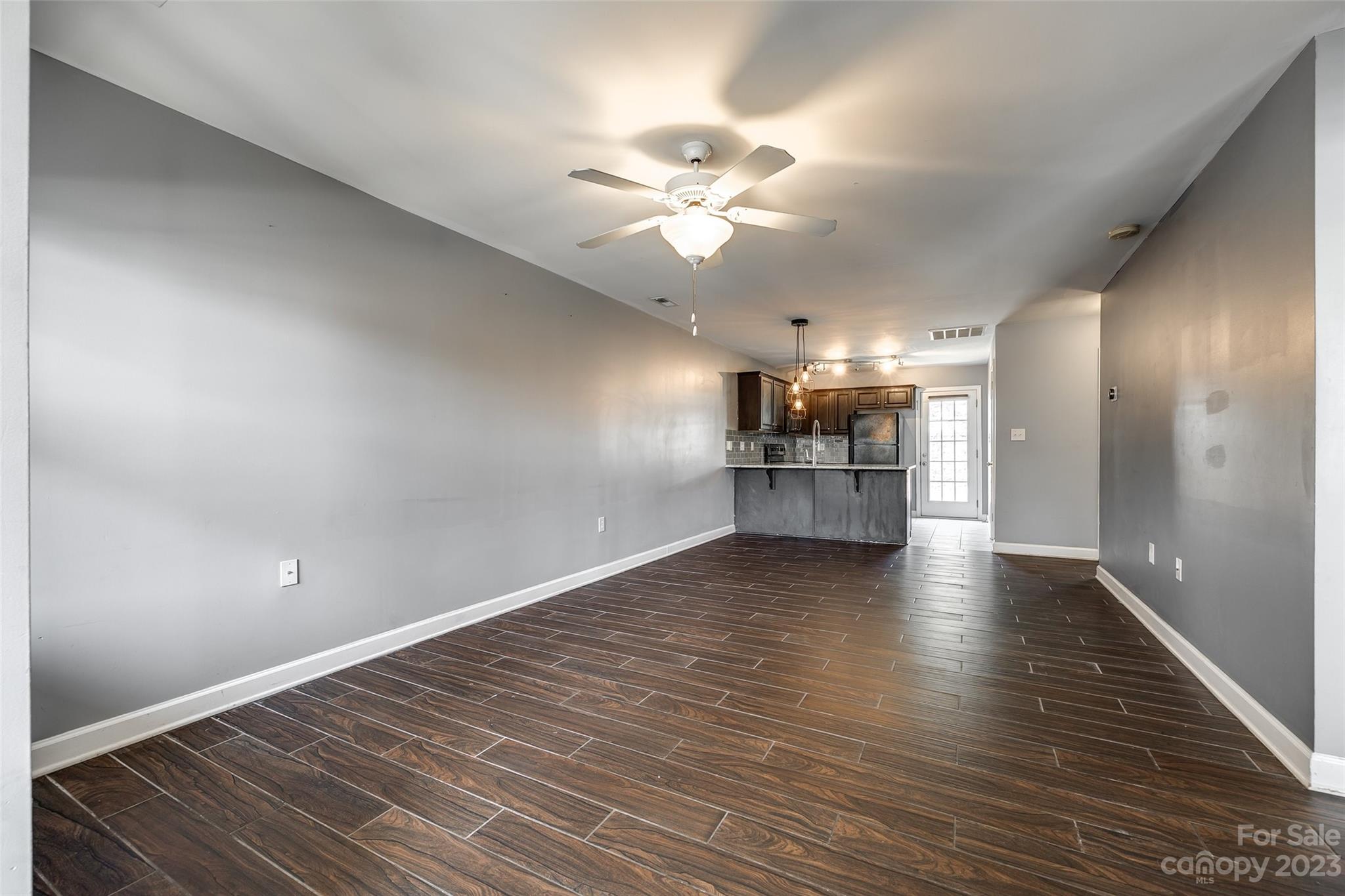 713 Waterfall Way Clover, SC 29710 - Photo 5 of 27 an empty room with wooden floor windows and a kitchen view
