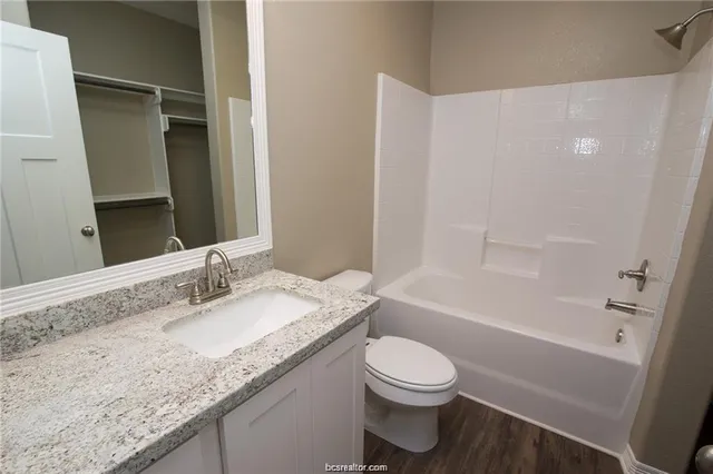 a bathroom with a granite countertop sink toilet and shower