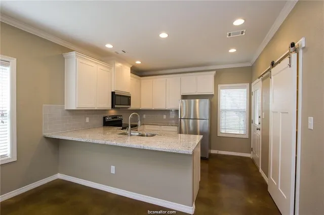 a kitchen with stainless steel appliances granite countertop a sink refrigerator and cabinets