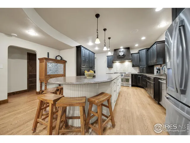 a kitchen with stainless steel appliances kitchen island granite countertop a sink refrigerator and cabinets