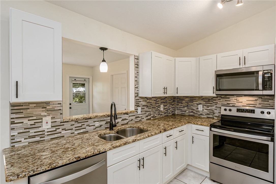 1121 Clearmont Street Sebastian, FL 32958 - Photo 12 of 31 a kitchen with stainless steel appliances granite countertop a sink stove and microwave