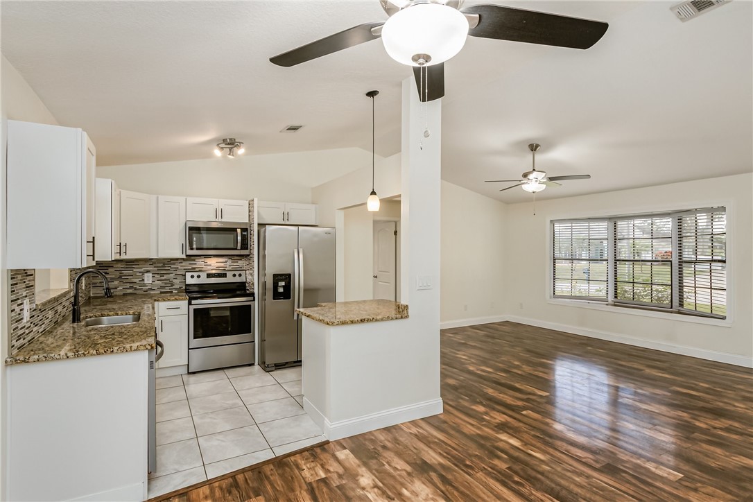 1121 Clearmont Street Sebastian, FL 32958 - Photo 14 of 31 a kitchen with stainless steel appliances kitchen island granite countertop a refrigerator and a stove top oven