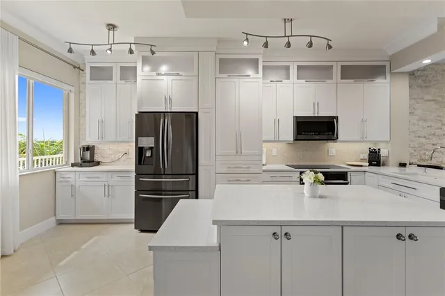 a kitchen with a refrigerator a microwave a sink and white cabinets