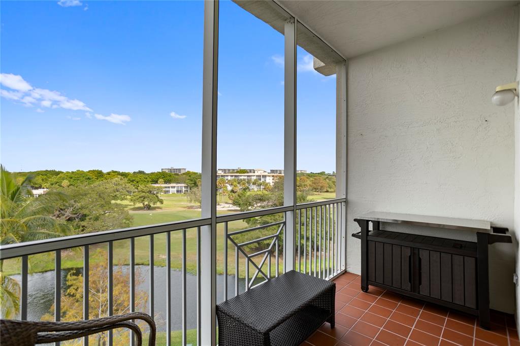 3500 Oaks Clubhouse Drive, Unit 505 Pompano Beach, FL 33069 - Photo 16 of 33 a view of a balcony with chairs and wooden fence