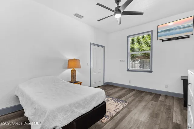an empty room with wooden floor and ceiling fan