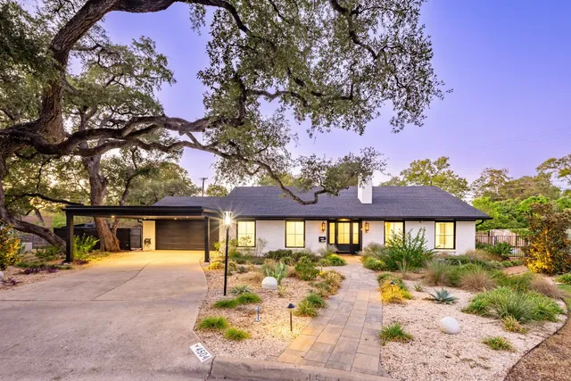 a view of house with yard outdoor seating and covered with trees