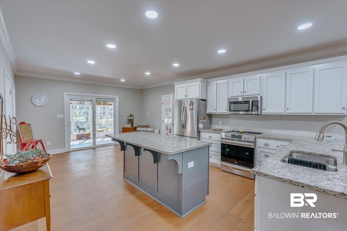 14160 Moffett Road Wilmer, AL 36587 - Photo 3 of 75 Kitchen with light wood-type flooring, ornamental molding, stainless steel appliances, a sink, and white cabinets