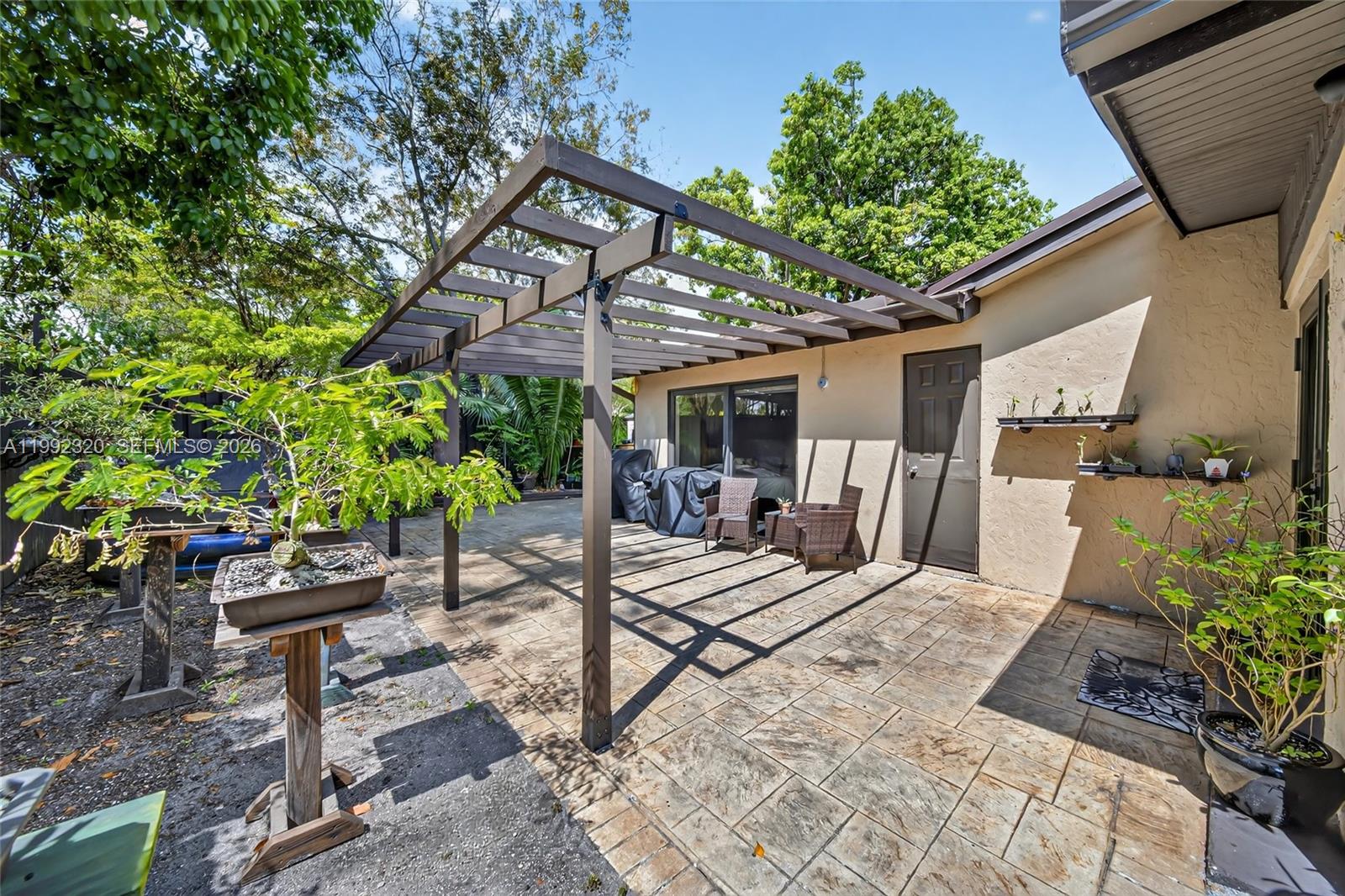 10861 Southwest 132nd Cir Court Miami, FL 33186 - Photo 39 of 42 a view of a patio with table and chairs potted plants and large tree