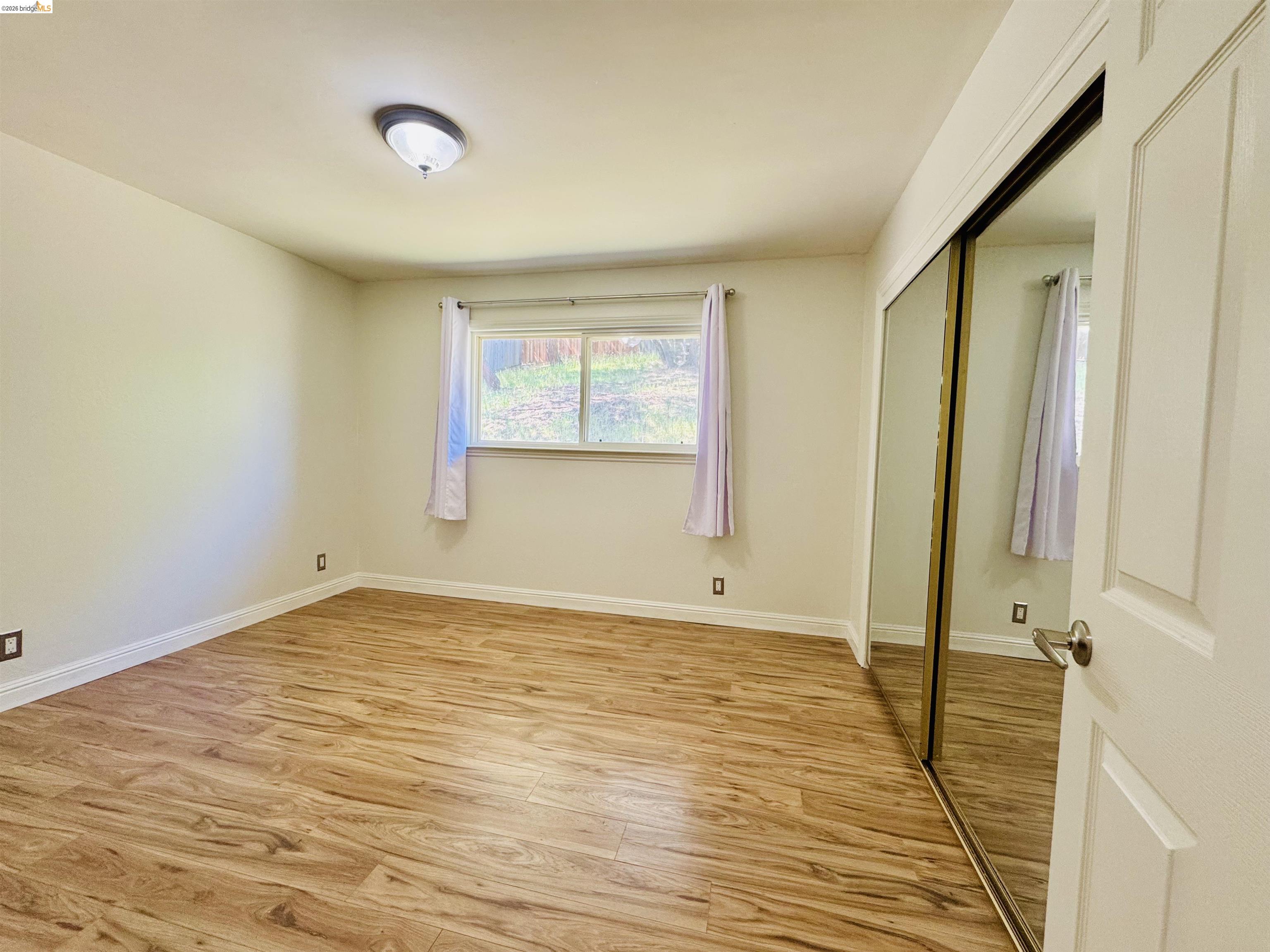 64 Washington Street Novato, CA 94947 - Photo 15 of 21 Room featuring wood-finish flooring, a window with exterior visibility, and a ceiling-mounted light fixture