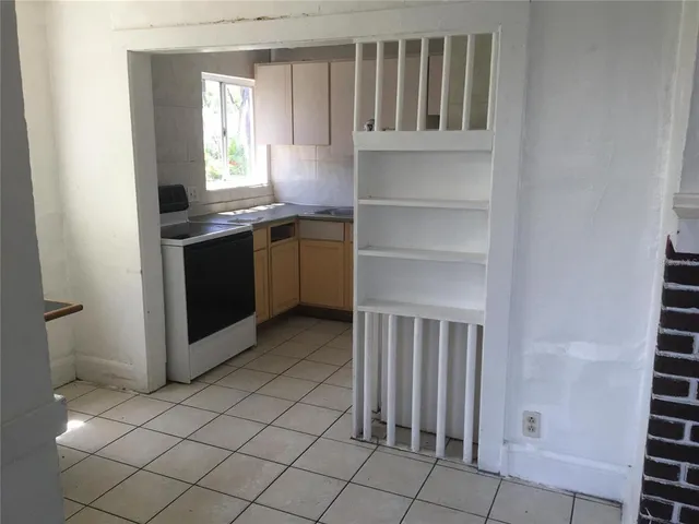 a kitchen with granite countertop a stove a sink and a refrigerator