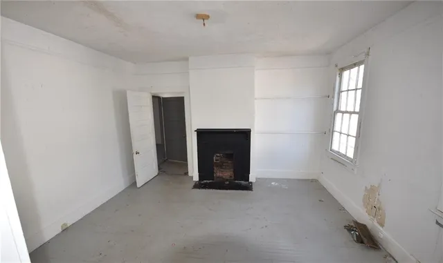 an empty room with windows and fireplace