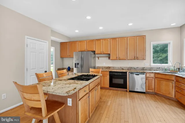 a kitchen with granite countertop kitchen island stainless steel appliances a stove a sink a refrigerator and cabinets