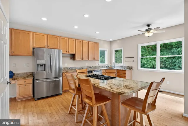 a kitchen with stainless steel appliances granite countertop a stove a refrigerator a sink a dining table and chairs