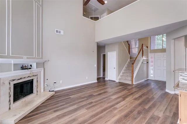a view of an empty room with wooden floor fireplace and a window