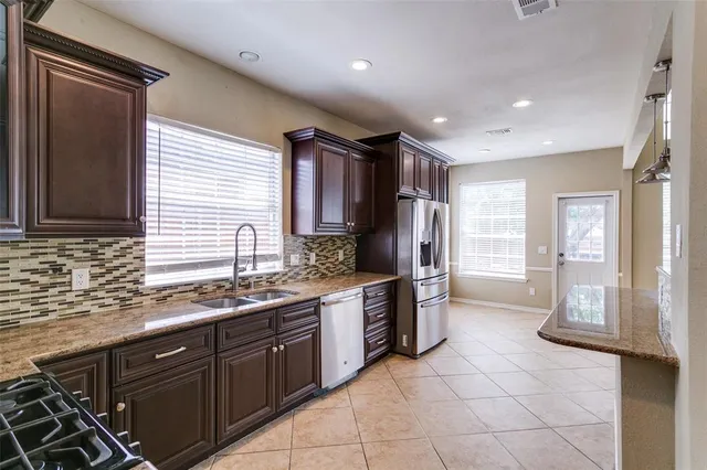 a large kitchen with stainless steel appliances a sink stove and cabinets