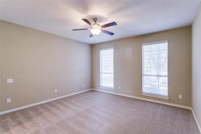a view of an empty room with window and chandelier fan