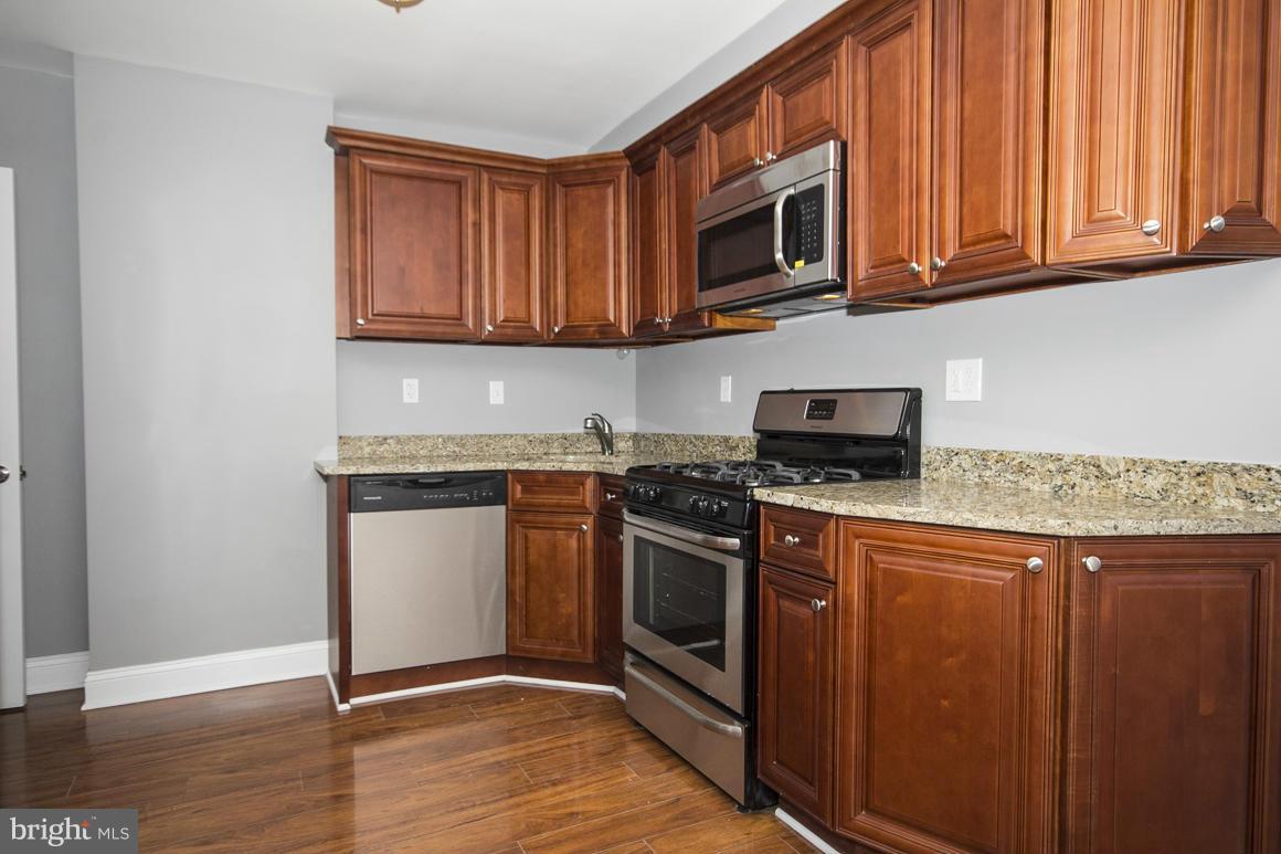 33 Eastship Road Baltimore, MD 21222 - Photo 3 of 23 a kitchen with stainless steel appliances granite countertop a stove top oven a sink dishwasher and microwave with wooden floor