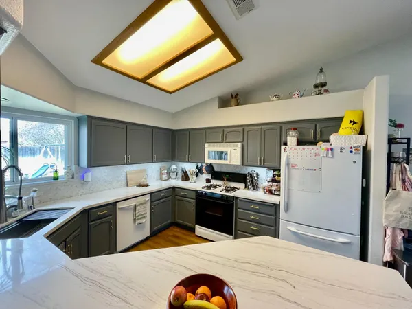 a kitchen with stainless steel appliances granite countertop a sink dishwasher stove and refrigerator