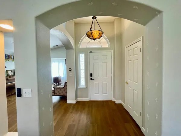 a view of a hallway with wooden floor table and windows